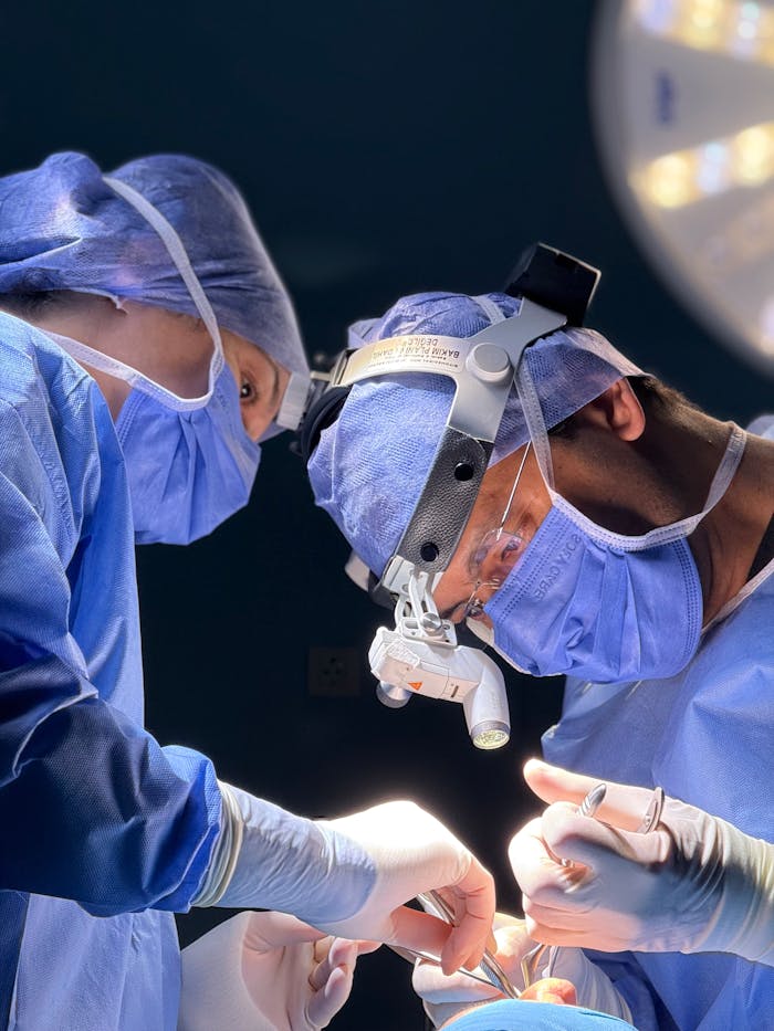 Two surgeons focus intently during a delicate operation, showcasing teamwork and precision in a medical setting.